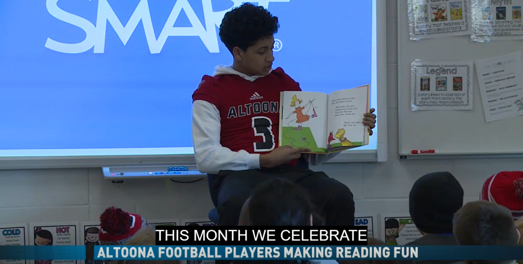 An Altoona football player reads to kids